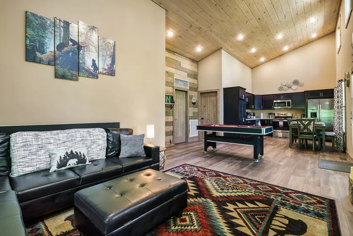 A cozy yet lively interior showcasing a black leather sofa, colorful area rug, pool table, and inviting artwork—capturing the essence of post-adventure family bonding through indoor games and relaxation.